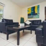 Living room with black leather couches in Steps to Recovery drug rehab facility
