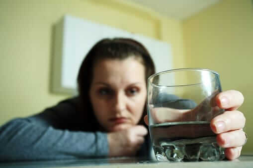 Woman concentrating on her drink knows she has some symptoms of alcoholism.