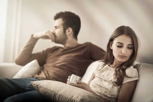 Couple on sofa puzzled about confusing signs of addiction.