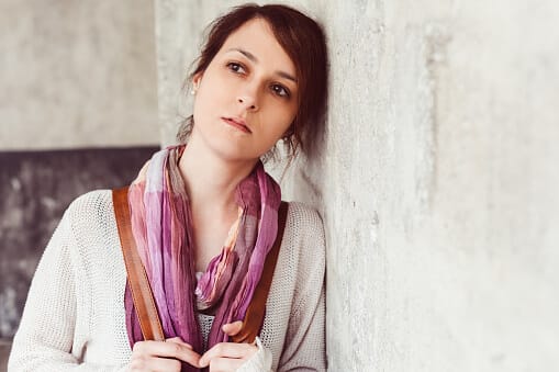Woman leaning against wall wondering about residential treatment centers.