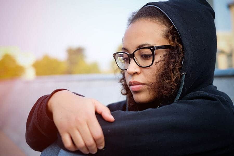 Young woman with glasses in hoodie realizing there is a psychological addiction in drug abuse.