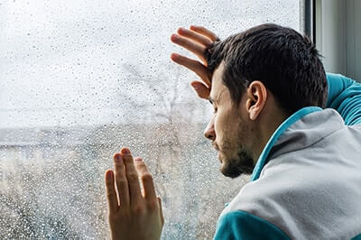 a man looking out a window looking for long term drug rehab