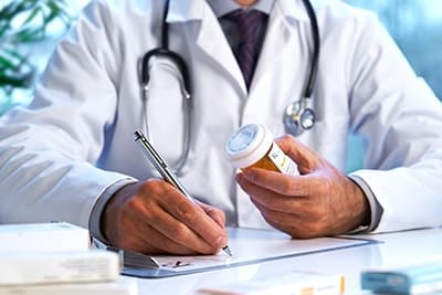 a doctor writing a prescription for a medication assisted treatment program