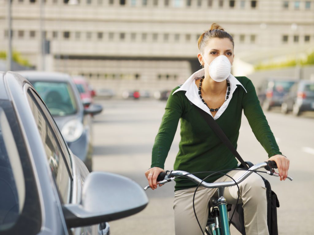 woman riding a bike and wearing a protective mask