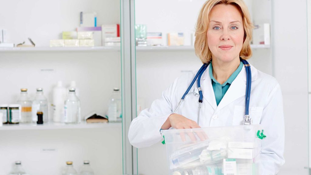 Mature pharmacist is putting medicine on shelves at pharmacy