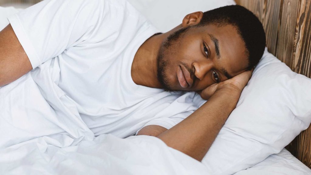 Depressed African American Man Lying Awake Thinking Of Problems And Having Insomnia In Bedroom At Home At Night. Male Stress And Depression, Sleeplessness And Apathy Concept.