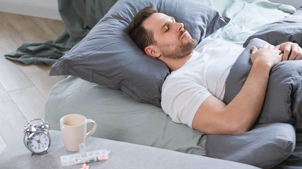 man sleeping with pills next to him
