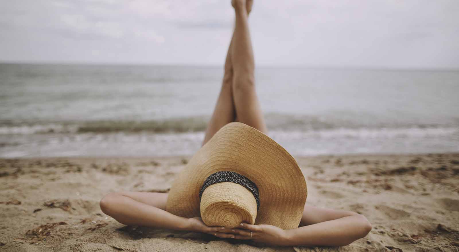 girl-with-big-hat-laying-on-the-beach