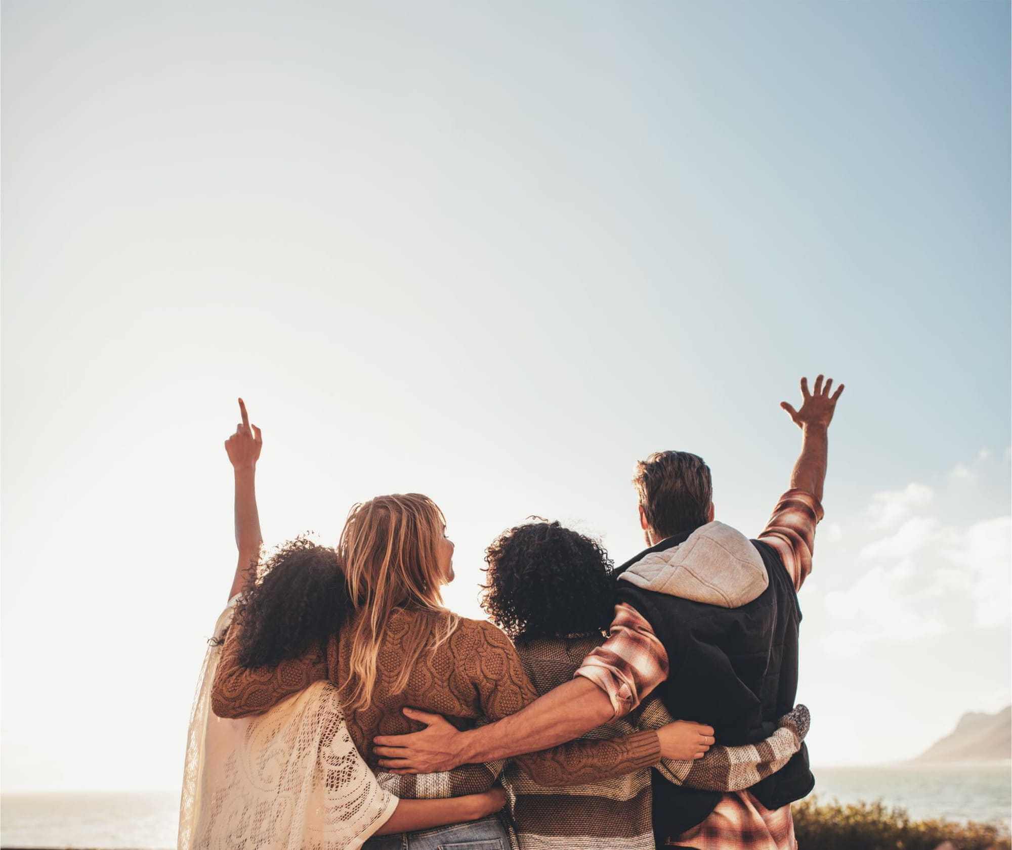 Group of four friends hugging on top of a mountain